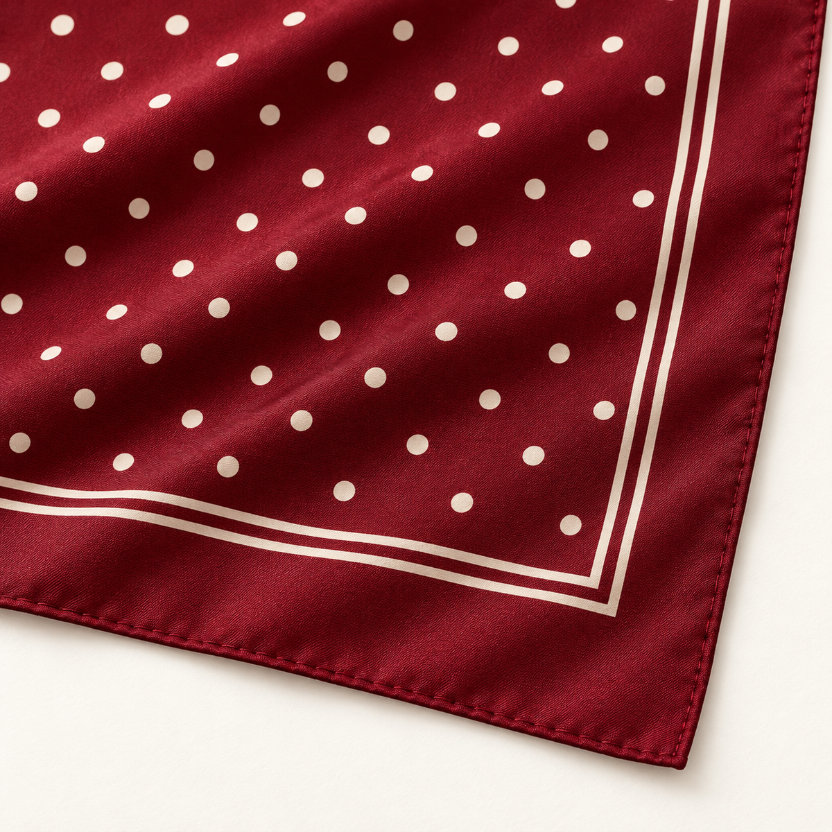 Close-up of ivory polka dots, double border lines and flat stitched burgundy hem